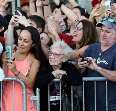 woman watching the moment in a crowd of people taking photographs of the moment